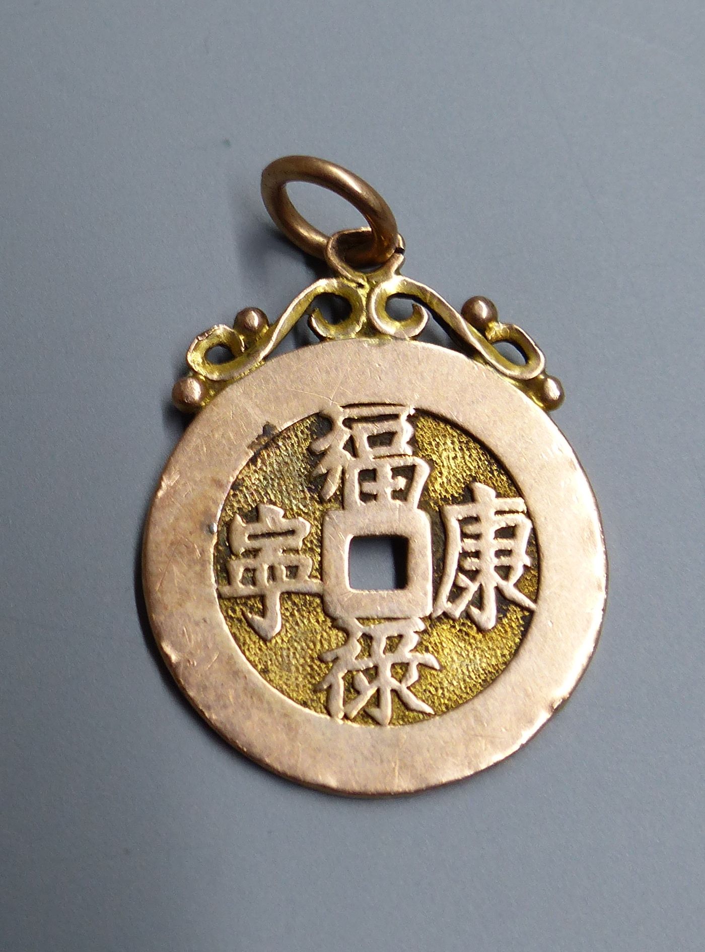 Eight assorted Chinese yellow metal amulets, four in the form of brooches, three pendants and a stick pin, 21.5 grams.